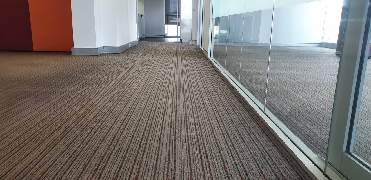 A corridor of cleaned striped carpet in Perth, dry and safe underfoot before anyone walks it, the standard falls risk demands in aged care.