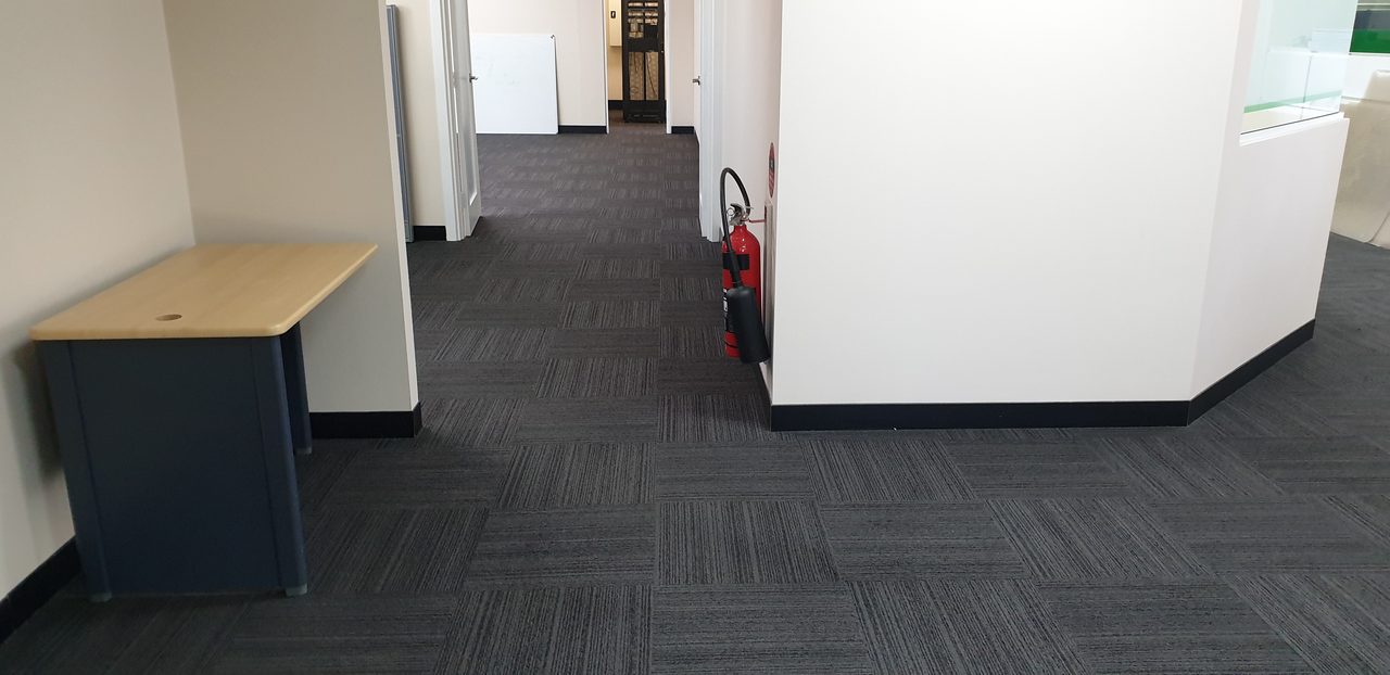 Charcoal carpet tiles through a Perth corridor and doorways, the kind of route where dedicated equipment stops contamination moving between areas.
