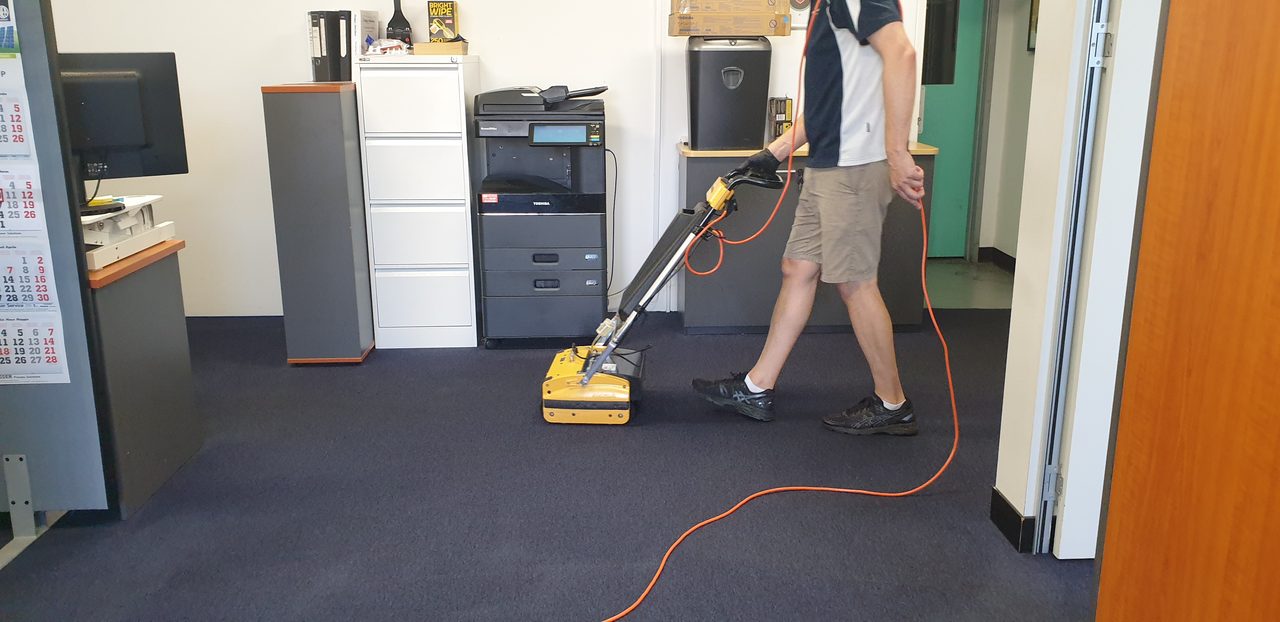 Dark blue office broadloom in Perth under our cylindrical brush machine, the method chosen on the site walk once we measure the floor and check the fibre.