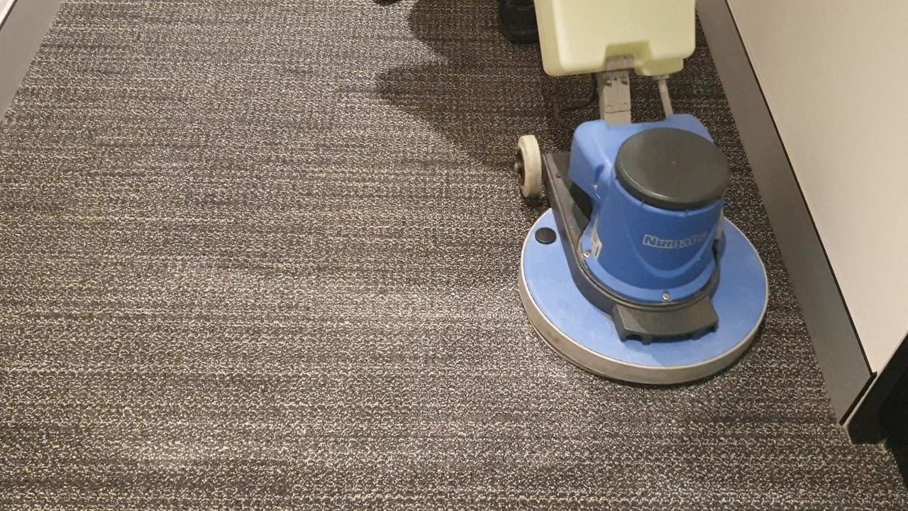 Our rotary machine on flecked carpet tiles beside a Perth office partition, cleaning the zone once smell and a moisture meter have traced the source.
