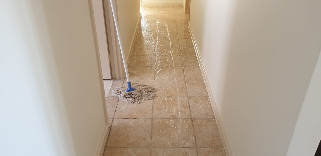 Cleaning solution worked across a tiled hallway floor in Perth, the tiles and grout washed before they are rinsed clean