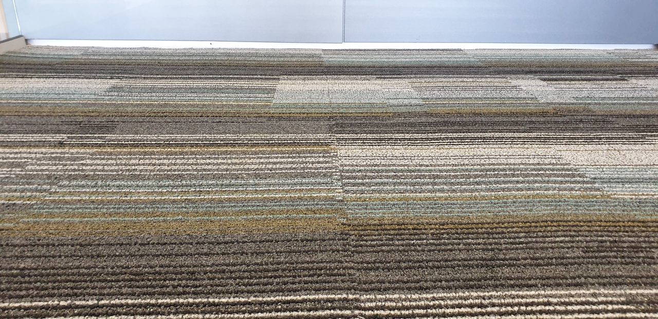 Striped olive, teal and charcoal carpet tiles in a Perth office, a floor whose life depends on getting abrasive soil out before it wears the fibre