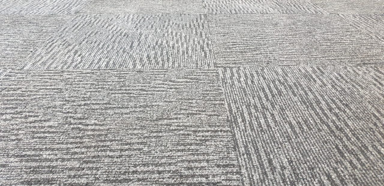 Pale silver carpet tiles laid quarter-turn in a Perth office, where proof of professional cleaning protects the warranty and the lease