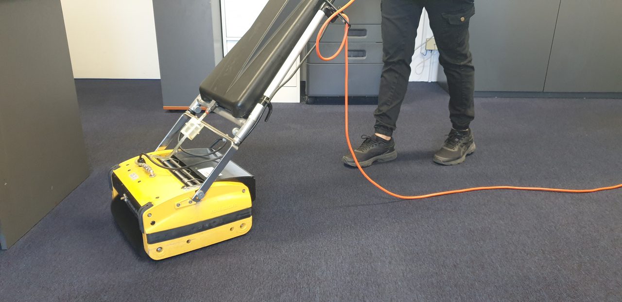 A cylindrical brush machine scrubbing navy office broadloom in Perth, a low moisture clean suited to the slower drying of a Perth winter