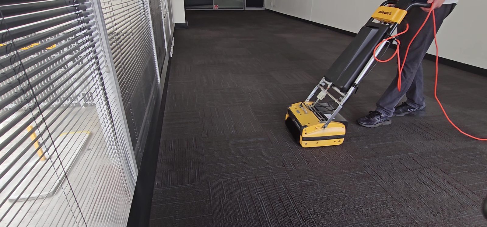 Our cylindrical brush machine working encapsulation through dark carpet tiles in a Perth office, the low moisture clean for lightly soiled floors.
