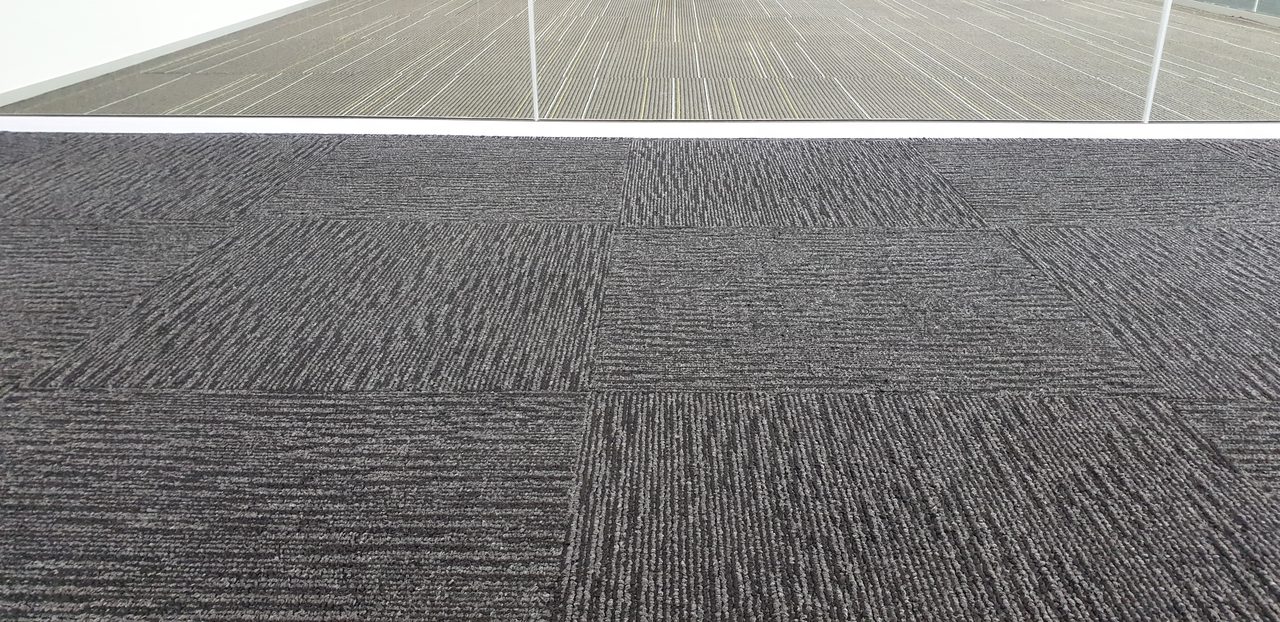 Charcoal quarter-turn carpet tiles in a vacated Perth office, cleaned so the floor is ready for the landlord's handover inspection