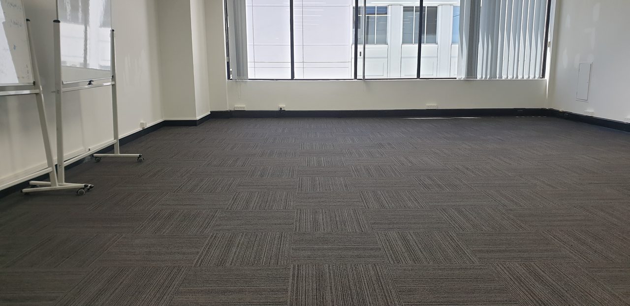 An empty Perth tenancy floored in charcoal carpet tiles, the make good clean done once the room is clear