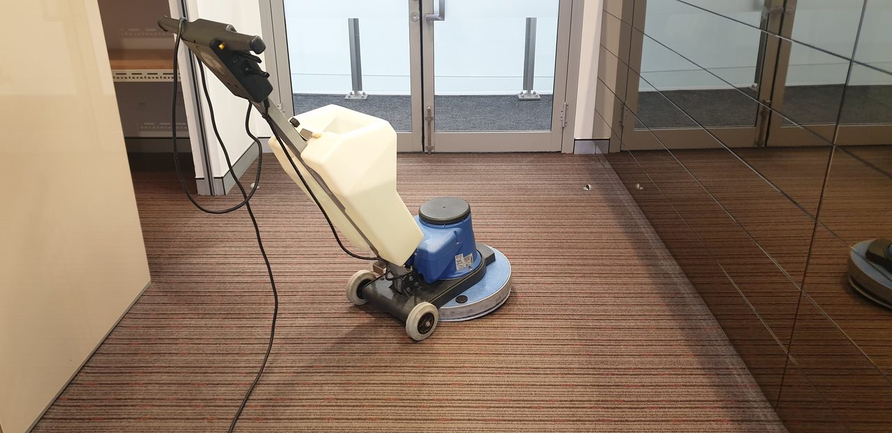 Red brown ribbed carpet in a Perth office lobby cleaned by our scrubbing machine, right up to the entry doors where soil arrives