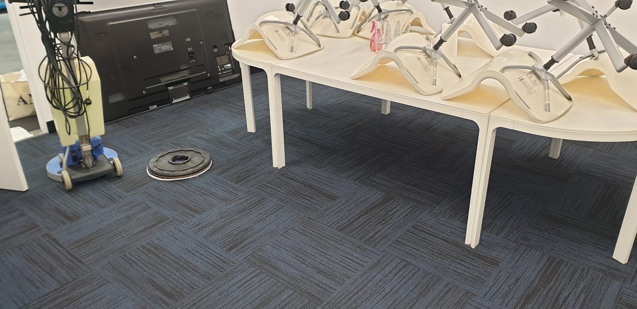 Chairs up on the tables while navy carpet tiles are cleaned in a Perth function room, timed so the floor is dry for the next booking