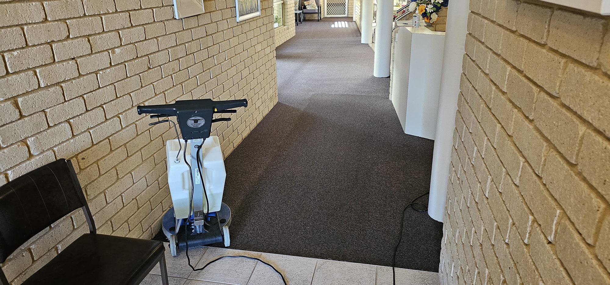 A brick walled walkway in a Perth building, its dark carpet cleaned the full length of the corridor