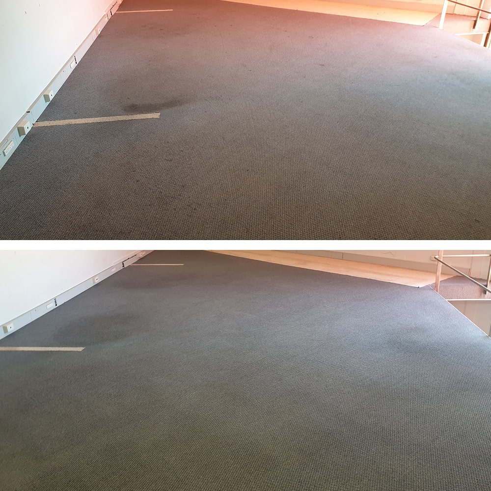 A dark spill patch on grey loop pile in an open Perth office, removed so the floor looks clean to its edges