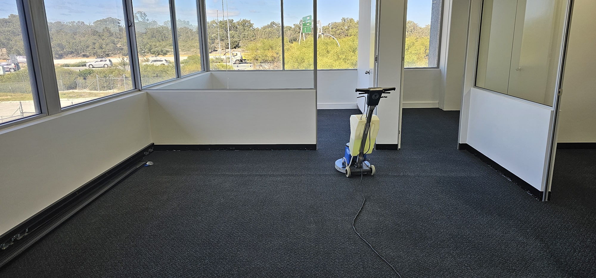 A vacant Perth corner office, its charcoal carpet cleaned while the room is clear of furniture
