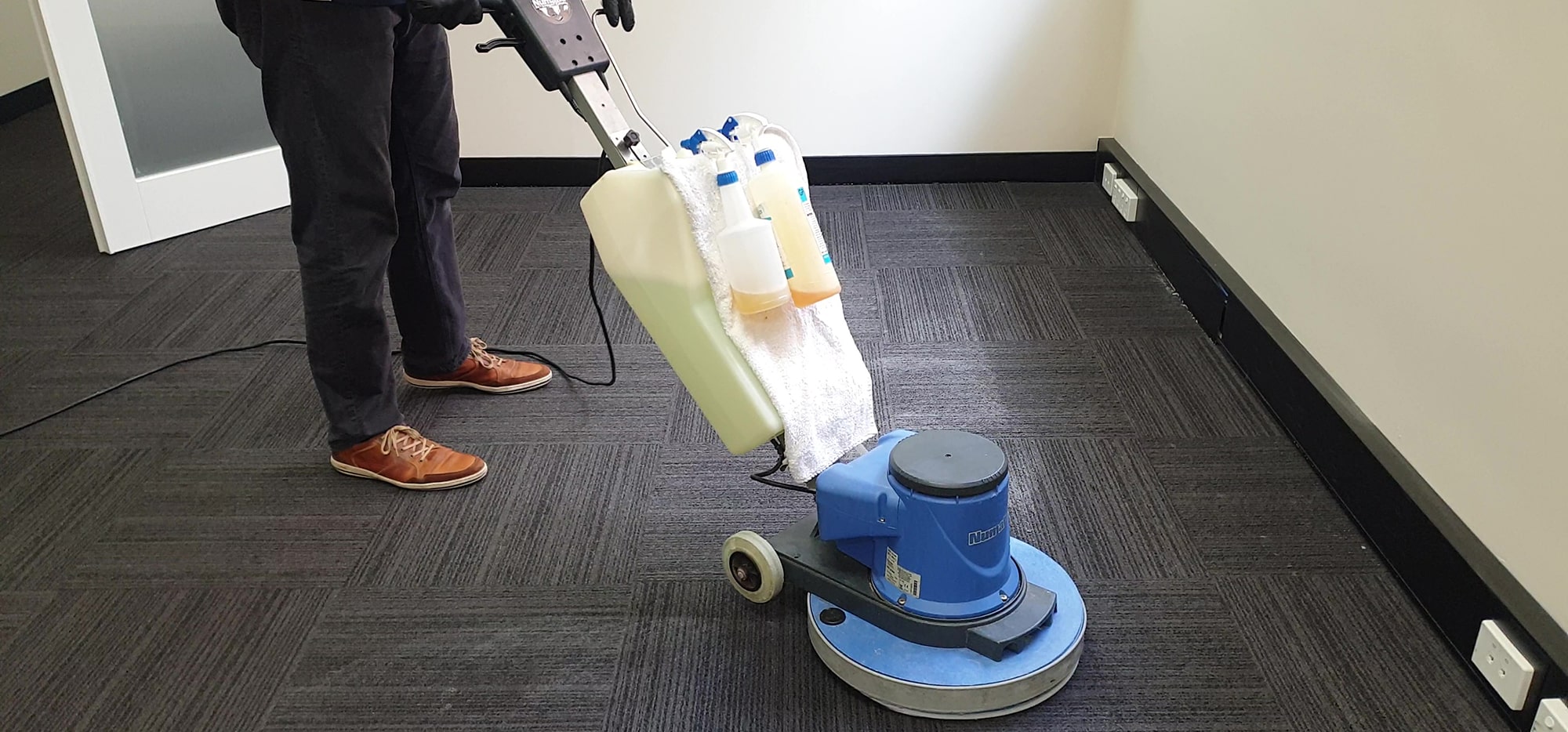 Our scrubbing machine taken right to the skirting on charcoal carpet tiles in a Perth office, so the edges get cleaned too