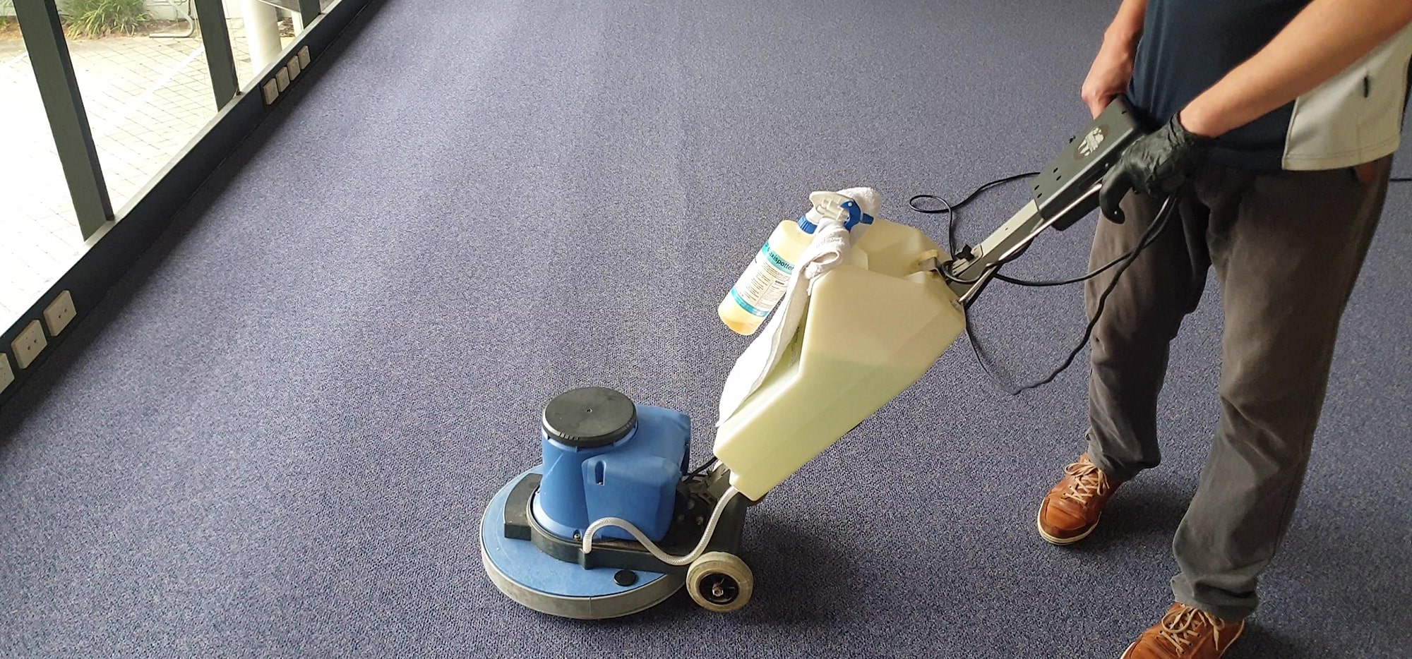 Our technician scrubbing navy office carpet in Perth, loosening the soil a vacuum alone leaves in the pile