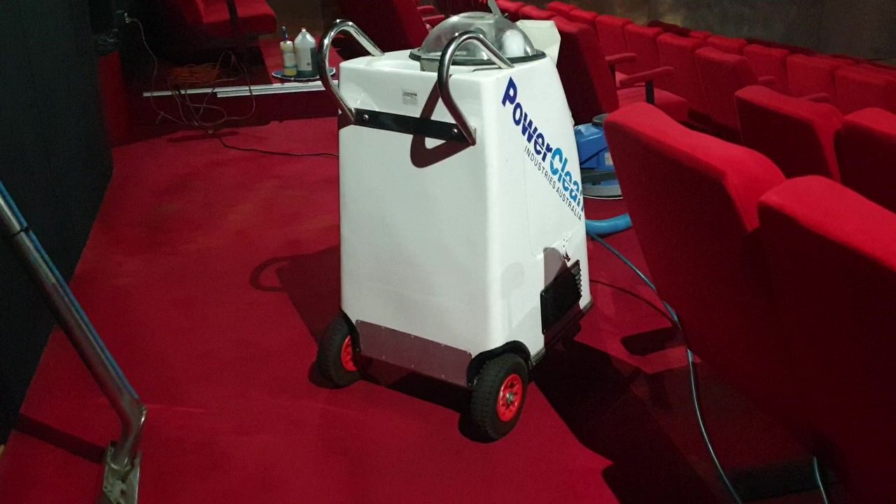 A portable extraction machine in the aisle of a Fremantle cinema, between rows of red seats.