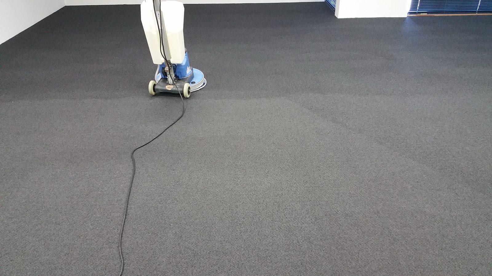An open-plan office in Perth mid-clean, our rotary machine working the dense charcoal carpet across the whole empty floor.