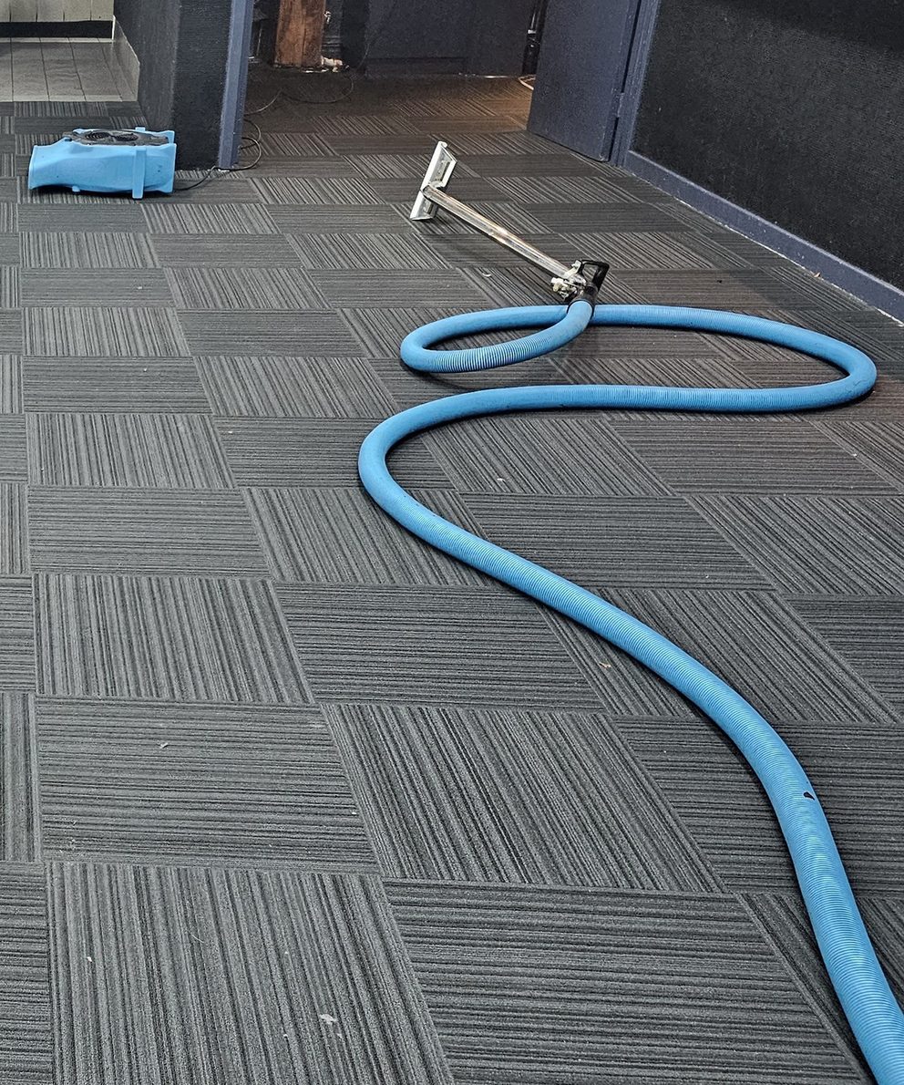 Truck-mounted extraction set up at a Perth function venue, the hose and wand laid on the carpet tiles and an air mover already running.