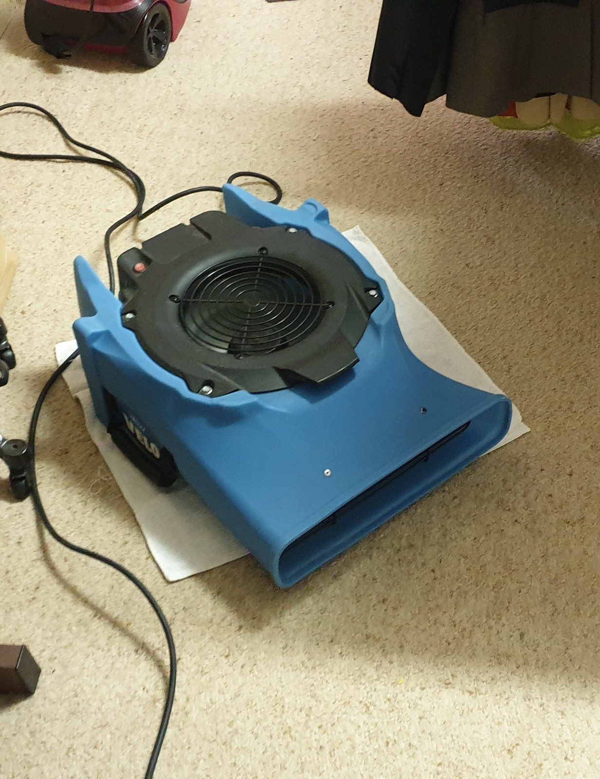 An air mover drying carpet in Perth after a leak, set on a protective sheet and run until the floor reads dry.
