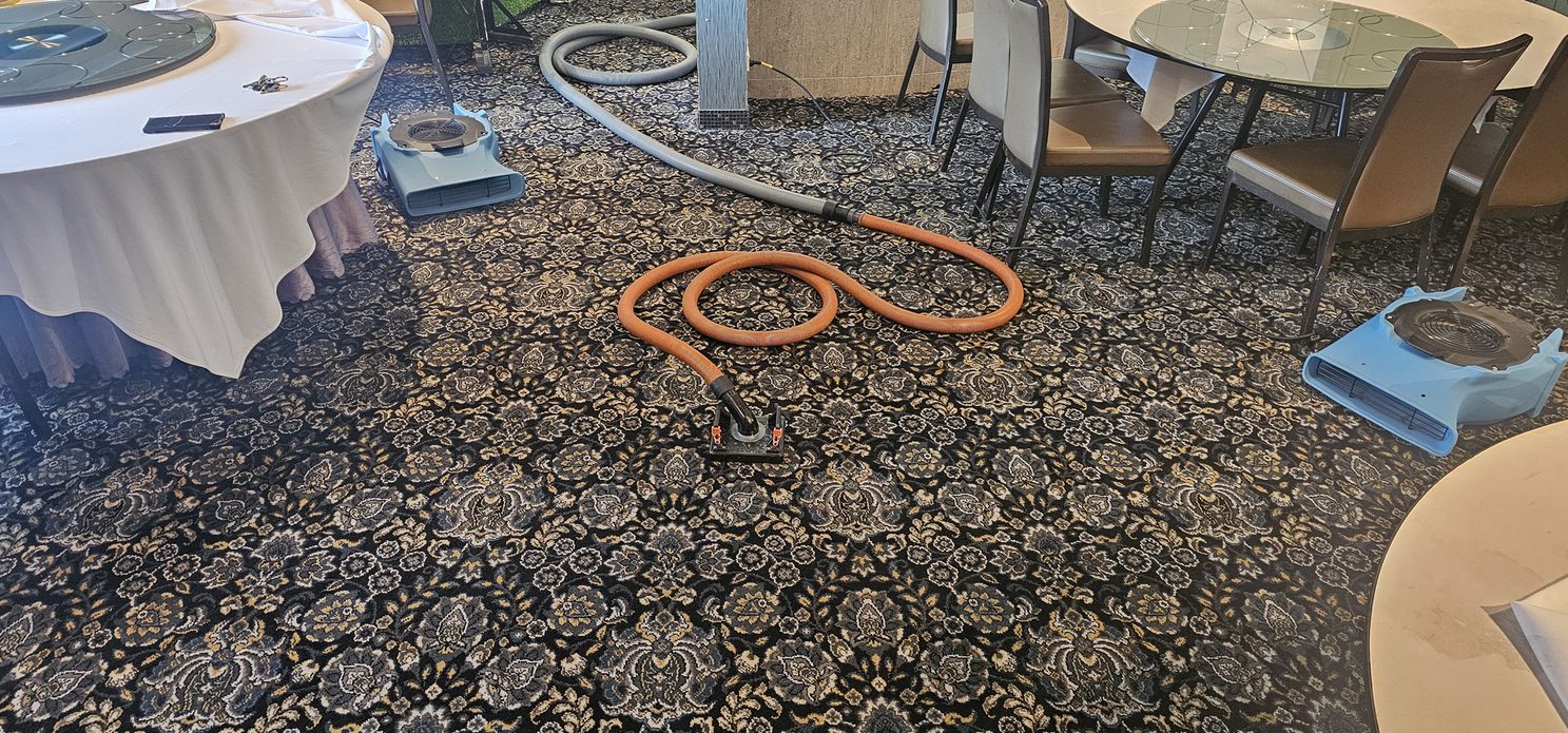 Water damage restoration in Perth, flood extraction and air movers drying the carpet of a function room between its dining tables.